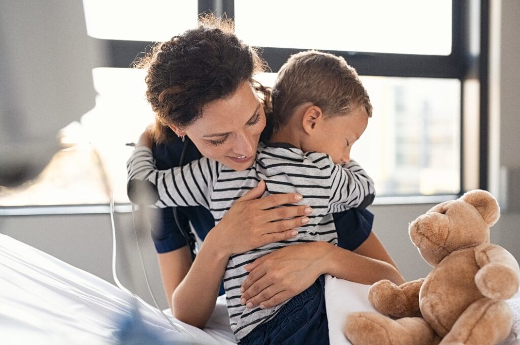 Süßes Kind, das eine Krankenschwester im Krankenhaus umarmt